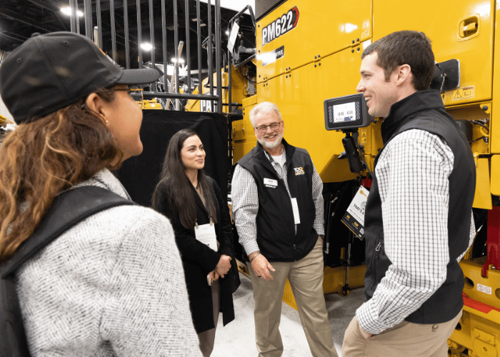 Industry professionals networking and discussing sustainable heavy equipment solutions at world of asphalt